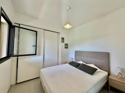 a bedroom with a white bed and a window at T2 à 200m des plages in Propriano