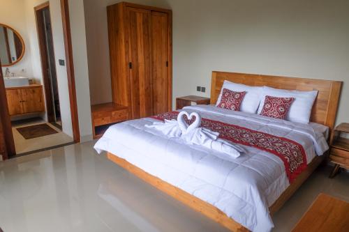 a bedroom with a large bed with red and white pillows at Loka Shanti Mas in Mantaak