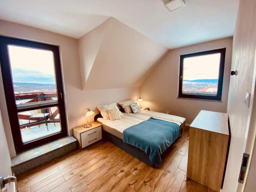 a bedroom with a bed and two large windows at Dom 8-osobowy z jacuzzi, balią, sauną - Agroturystyka u Moniki in Masłów