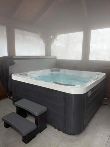 a jacuzzi tub with a stool in a bathroom at Bogatu Vendégház in Bogács