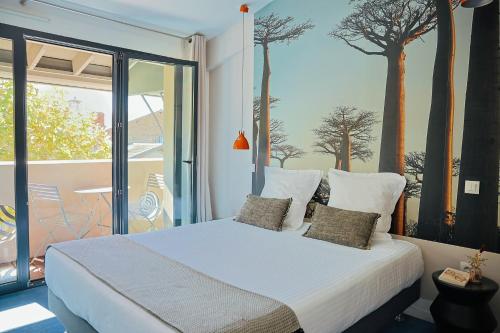 una camera da letto con un letto con alberi sul muro di L’Échappée Belle a LʼIsle-Jourdain