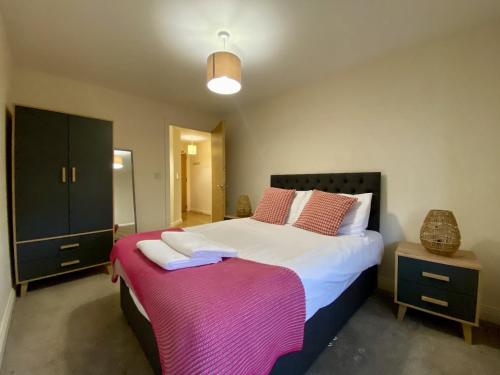 a bedroom with a large bed with a pink blanket at Wokingham Stylish Two Bedroom Apartment in Wokingham