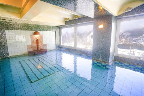 a swimming pool in a building with blue tiles at Trip7湯沢天空温泉ホテル in Yuzawa