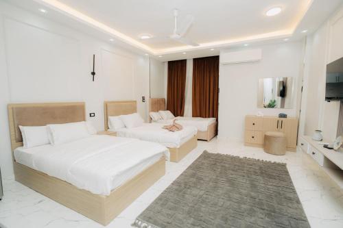 a white bedroom with two beds and a television at ElMena House Luxor in Luxor