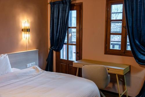 a bedroom with a bed and a desk and a window at Αρχοντικό Παπαγιάννη in Edessa