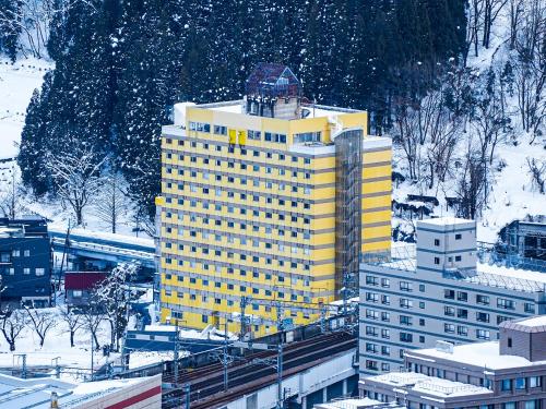 a yellow building with snow on top of it at Trip7湯沢天空温泉ホテル in Yuzawa
