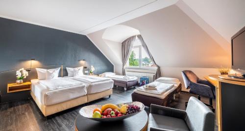 a hotel room with a bed and a bowl of fruit on a table at PLAZA INN Heidehof in Hermannsburg