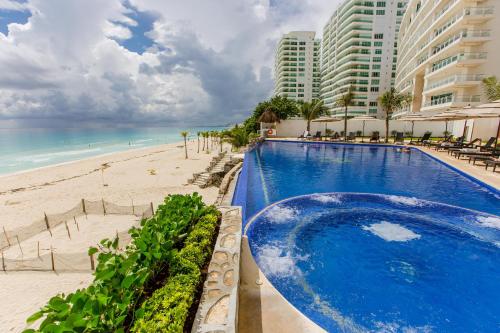 a swimming pool next to a beach and some buildings at Condominio Girasol OceanView in Cancún