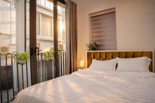 a bedroom with a large white bed and a window at AimeeHouse - Trích Sài in Hanoi