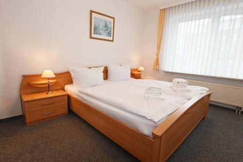 a bedroom with a bed with white sheets and a window at Bernstein Mare-Supreme Wohnung 4 in Büsum