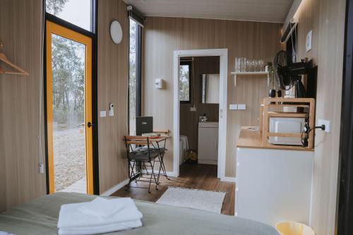 a room with a bed and a kitchen with a table at Pigeon Pair Tiny Houses by Tiny Away in Tallarook