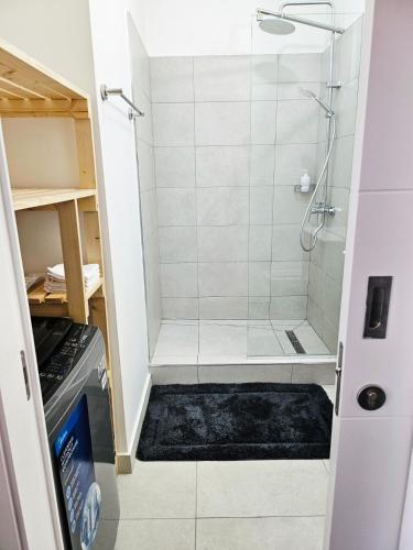 a walk in shower with a glass door at Friendly & Warm in Tamarin