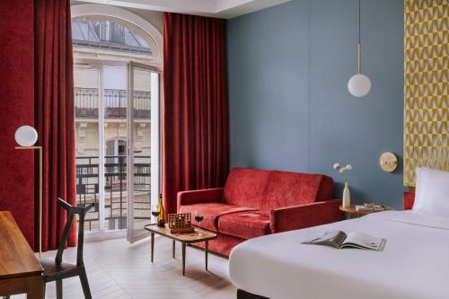 a hotel room with a bed and a red couch at Hôtel Atala Champs Elysees in Paris
