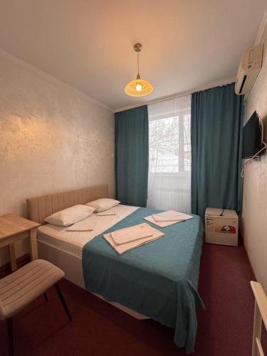 a bedroom with a bed with blue sheets and a window at Гостиница TERRA in Almaty