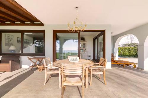 a dining room with a wooden table and chairs at Albarella Family Villa with Private Pool and Garden in Isola Albarella