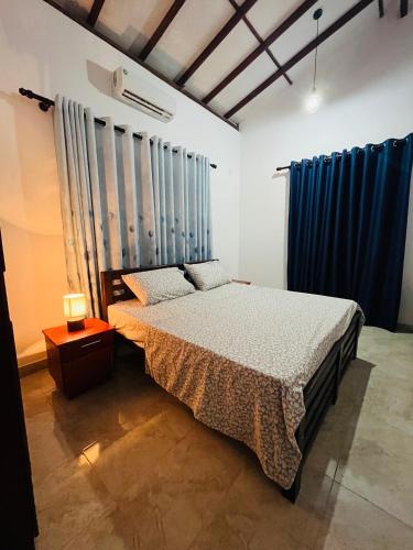 a bedroom with a bed and blue drapes at Manthraa Holiday Apartment in Ratgama Hegoda