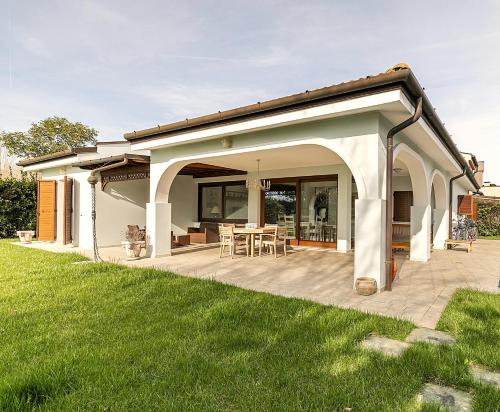 a covered patio with a table and chairs at Albarella Family Villa with Private Pool and Garden in Isola Albarella