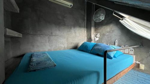 a bed with blue sheets in a room at Shelter Hostel Malang in Malang