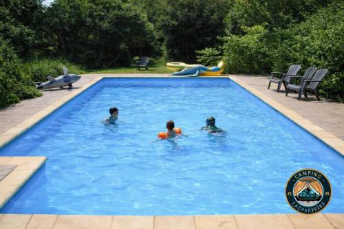 three people swimming in a swimming pool at Ingerichte safaritent in Saint-Priest-en-Murat