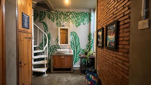 a bathroom with a sink and a wall with plants at Shelter Hostel Malang in Malang