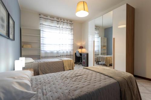 a bedroom with two beds and a mirror at Bicocca Urban Suite - SELF CHECKIN WIFI in Novara