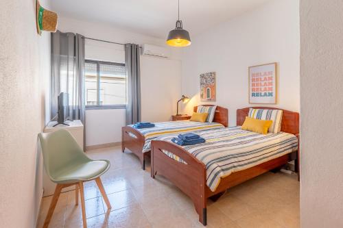 a bedroom with two beds and a chair in it at Hospedaria Portuguesa in Alpiarça