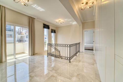 a hallway with a staircase in a home with windows at Carrington Holidays in Kyrenia