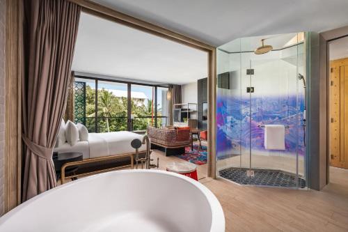 a bathroom with a tub and a bedroom at Hotel Indigo Phuket Patong by IHG in Patong Beach