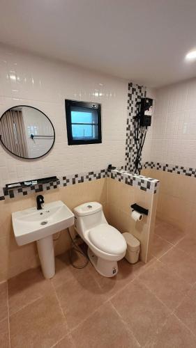 a bathroom with a toilet and a sink and a mirror at NICHA Cafe' & Resort in Ban Thap Chek Ha