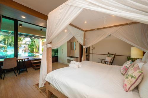 a bedroom with a canopy bed and a dining room at Baan SanSuk Pranburi - Beach Front & Pool Villa in Pran Buri