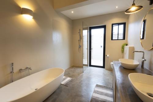 a bathroom with two sinks and a large tub at Villa Kolobe in Hoedspruit