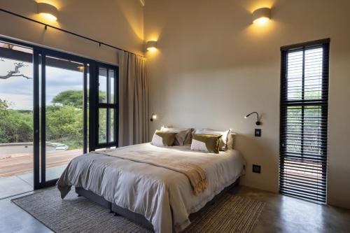 a bedroom with a large bed and a large window at Villa Kolobe in Hoedspruit