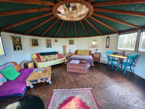 a living room with a large ceiling with a couch and a table at Galtee Glamping in wooden yurt in Mitchelstown