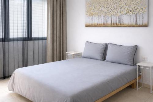 a bedroom with a white bed with a painting on the wall at Stylish Tel Aviv in Tel Aviv