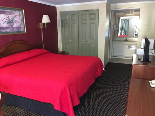a hotel room with a red bed and a television at FairBridge Inn Express Merrillville in Merrillville