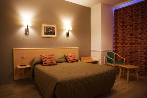 a bedroom with a bed with two pillows on it at Hôtel du Cheval Rouge in Versailles