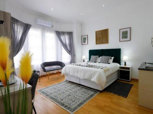 a white bedroom with a bed and a chair at Riveria Guest Lodge and SPA in East London