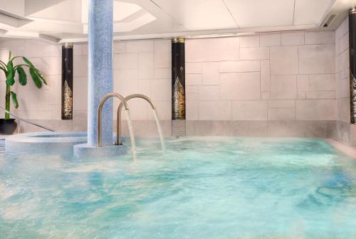 a hot tub with blue water and two faucets at Careys Manor Hotel & SenSpa in Brockenhurst