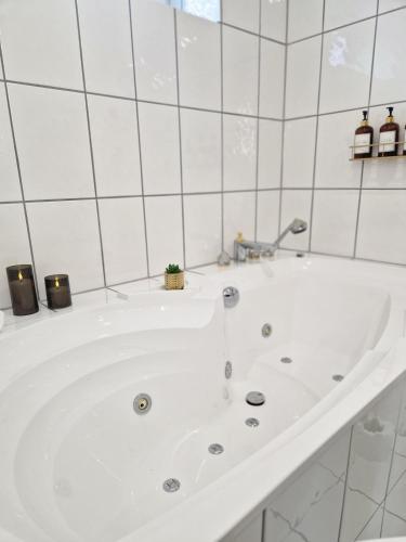 a white bath tub in a white tiled bathroom at Viktoria Apartment in Speicher