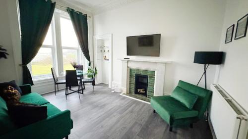 a living room with a green couch and a fireplace at Seaview apartment in Rothesay in Rothesay