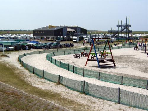 einen Spielplatz mit Schaukel und Spielplatz in der Unterkunft FeWo Schwarz in Dornumersiel