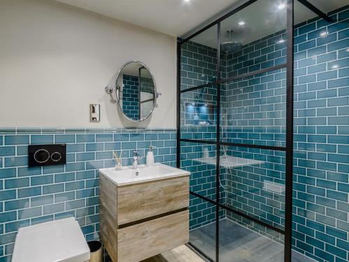 a bathroom with a sink and a shower with blue tiles at 3 Bed in Alnwick oc-77571 in Craster