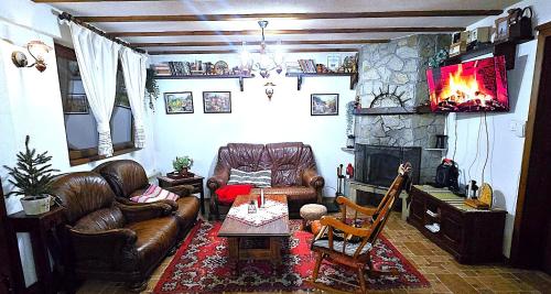 a living room with leather furniture and a fireplace at Къща за гости Начовата къща Стойките, Пампорово in Vodata
