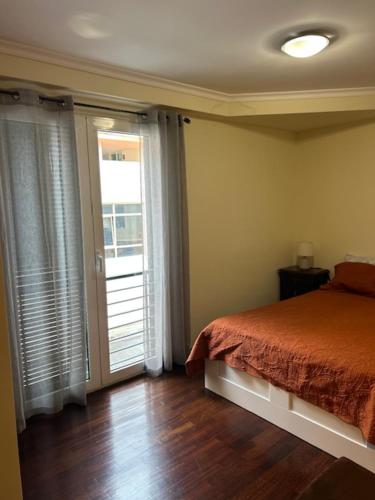 a bedroom with a bed and a sliding glass door at Caniço Easy Stay in Caniço