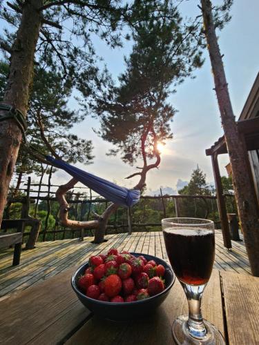 a bowl of strawberries and a glass of wine on a table at Gluba Treetop Cabins Furunåla in Harkmark