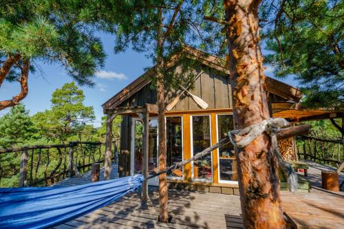 a tree house with a hammock in front of it at Gluba Treetop Cabins Furunåla in Harkmark