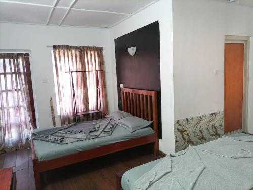 a bedroom with two beds and two windows at Cool feel rest and cafe in Nuwara Eliya