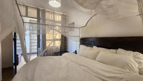 a bedroom with a white bed and a window at Kamakis Motel & Lounge in Ruiru