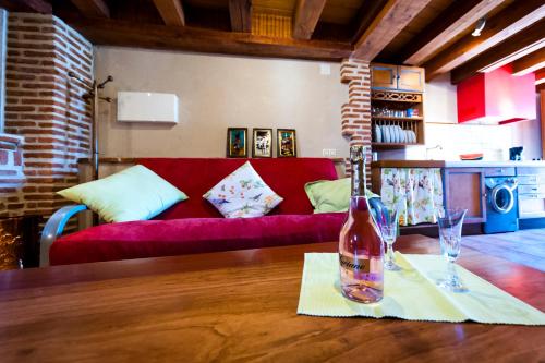 a bottle of wine on a table with a red couch at Villa Don Juan II in Segovia