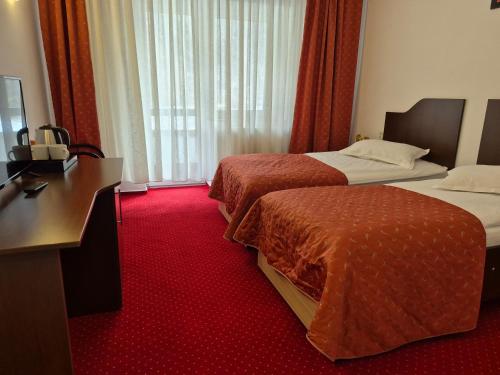 a hotel room with two beds and a desk at Cristal Sinaia in Sinaia